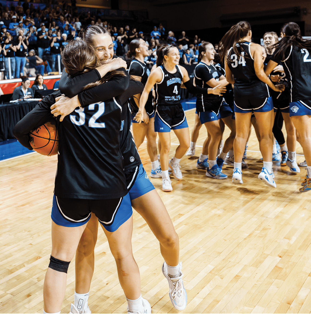 A group of women hugging each other on a basketball court. Description generated by AI