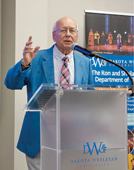 A man is giving a speech at a podium. Description generated by AI