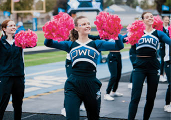A group of cheerleaders in pink and blue uniforms. Description generated by AI